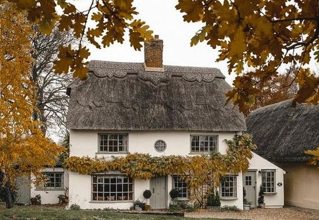 Piękny jesienny dom z wzorzastym trzcinowym dachem i wykuszowymi oknami...