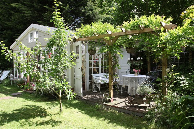 Biały ogrodowy domek z pergolą...