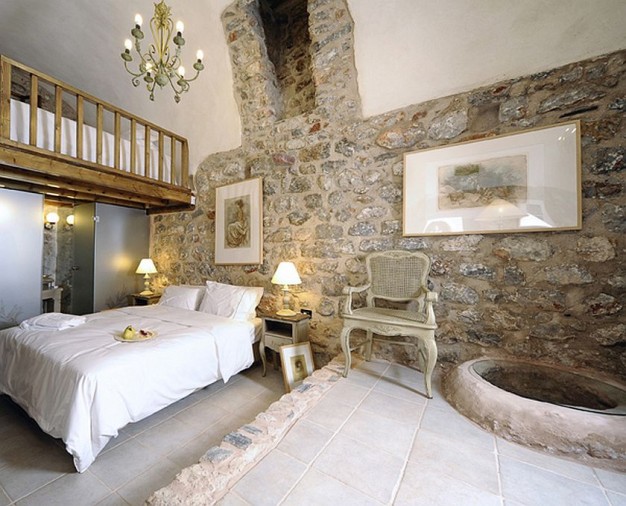 Biała sypialnia z kamiennym fragmentem muru...