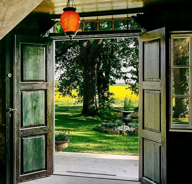 Zielone drzwi wiejskiego domu otwarte na pole rzepaku...