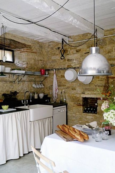 Kamienna kuchnia z białym belkowanym sufitem...